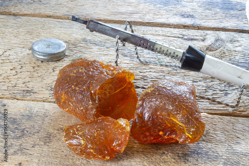 Fotografie large pieces of rosin and a soldering iron on a stand, rosin for soldering and a