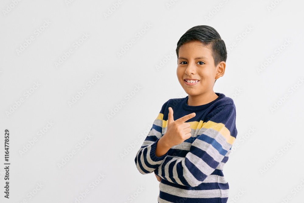 Portrait of a smiling boy confidently pointing to the side, wearing a colorful striped sweater, posing in front of a minimalist white background. Concept of enthusiasm and positivity Portrait of a smiling boy confidently pointing to the side, wearing a colorful striped sweater, posing in front of a minimalist white background. Concept of enthusiasm and positivity