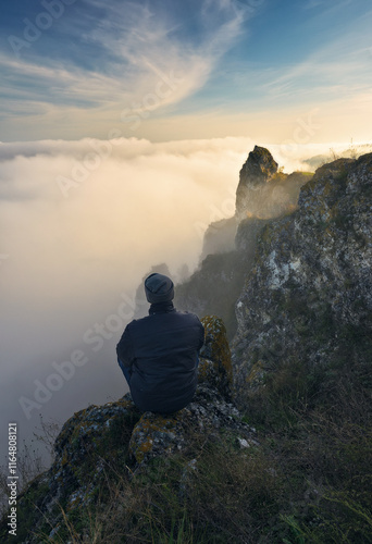 Autumn morning. Traveler on the top of rock above river valley with thick fog. Nature of Ukraine