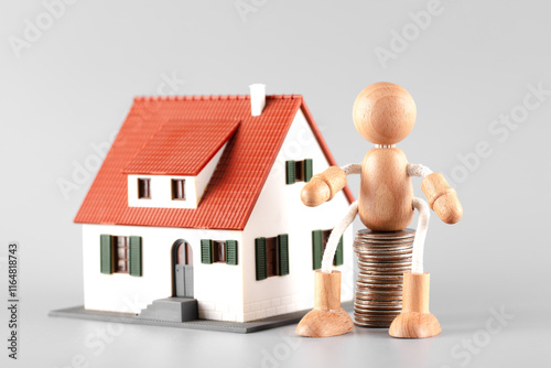A wooden man holding coins waiting to buy a house