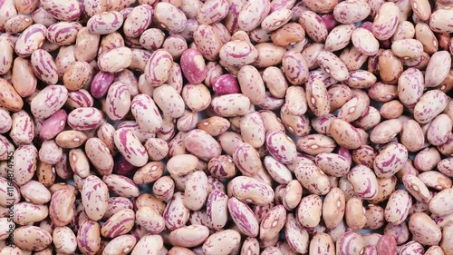 Top down view. Heap of dried uncooked speckled pinto kidney beans (barbunya), slider shot. Cooking, legumes, healthy eating, food preparation concepts. 4k
