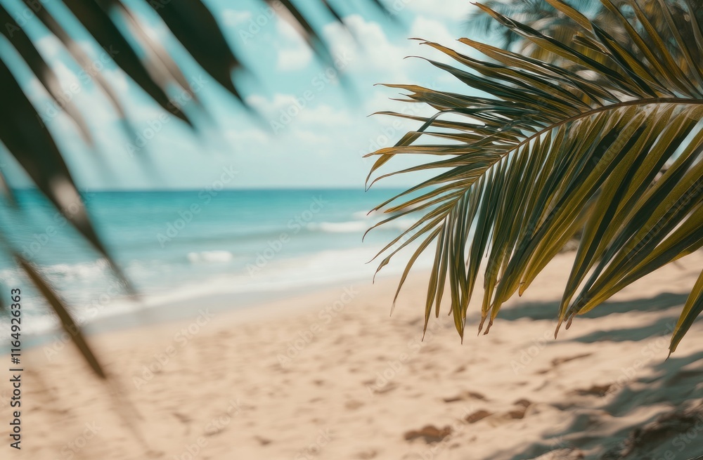 Fototapeta premium A beautiful tropical beach with palm leaves, a sandy shore, and a blurred background featuring ocean waves in the distance, capturing a summer vacation vibe. Ideal for vacation promotions, travel ads
