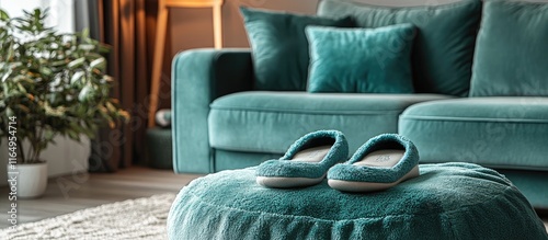 Cozy slippers beside a plush teal sofa in a warm living room setting exuding comfort and inviting relaxation for cozy moments at home