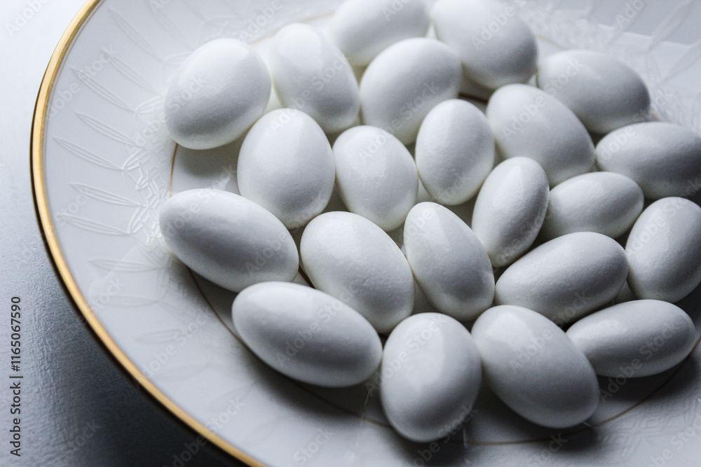 close-up of candy coated white jordan almonds arranged for festive occasion wedding reception gold trim plate background close-up of candy coated white jordan almonds arranged for festive occasion wedding reception gold trim plate background