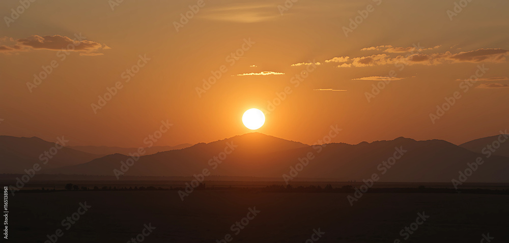 Fototapeta premium The rising sun casting a warm, golden glow, creating long shadows that emphasize the stillness of the moment.