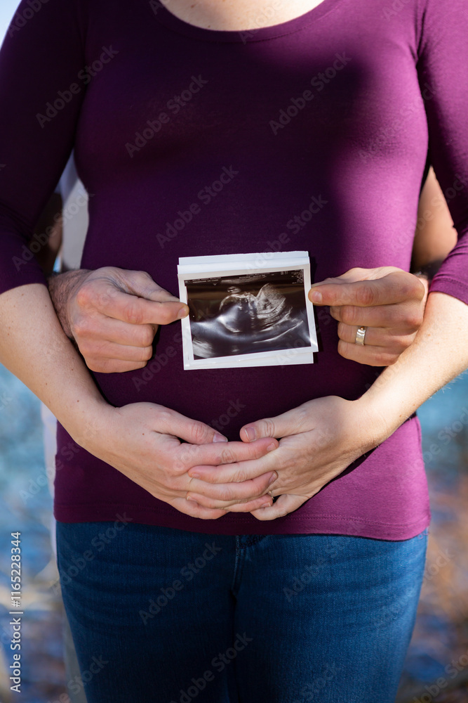 Soon to be parents pose with ultrasound photo in front of mother Soon to be parents pose with ultrasound photo in front of mother