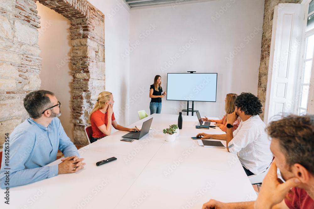 Obraz premium Marketing team following presentation on a white screen in meeting room