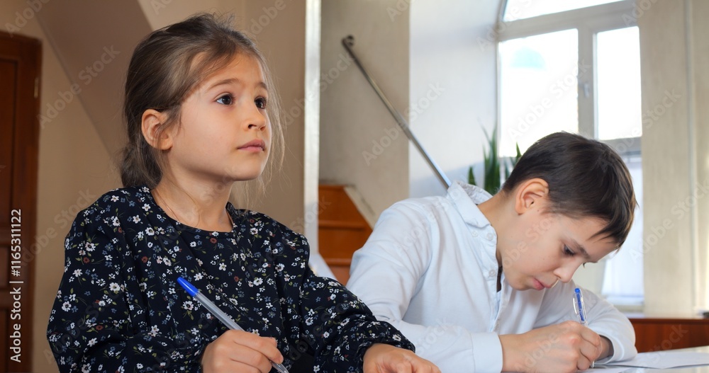 Students working intently at desks, writing and concentrating during classroom learning, capturing academic focus and educational engagement. Concept teaching children to write Students working intently at desks, writing and concentrating during classroom learning, capturing academic focus and educational engagement. Concept teaching children to write