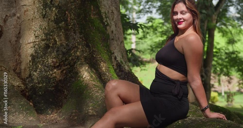 With the sun shining brightly, a Latina woman enjoys the lush beauty of a Caribbean park in a summery dress. photo