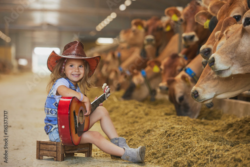 Charming child in a cowboy costume sings for cows on a farm in Denmark