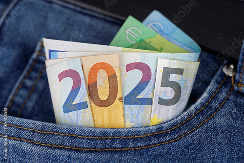 cash in the trouser pocket shows the year 2025, euro banknotes in blue jeans symbolize wealth or tax changes in the new year in europe photo