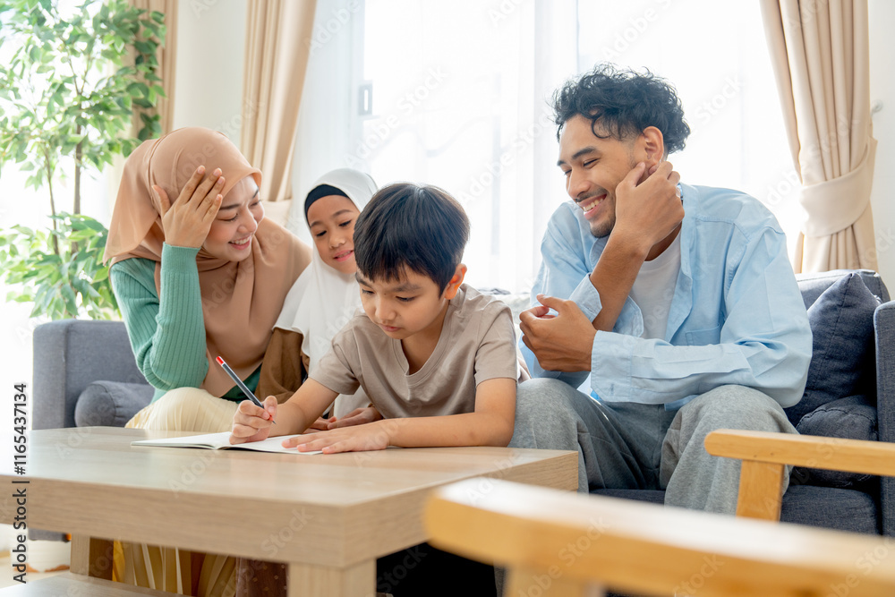 Side view muslim family with mother, father and daughter sit and cheer little boy for writing in living room of their house. Side view muslim family with mother, father and daughter sit and cheer little boy for writing in living room of their house.