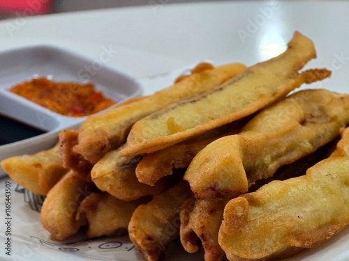 A plate of golden fried banana fritters served with dipping sauces. The dish highlights a popular snack or dessert, showcasing crispy batter and sweet flavors, ideal for promoting traditional cuisine  photo