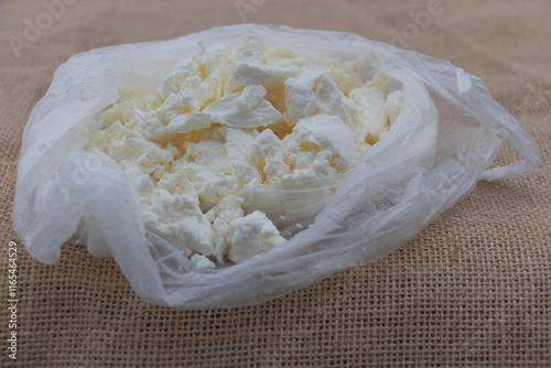 A plastic bag of soft white cheese on a burlap background photo