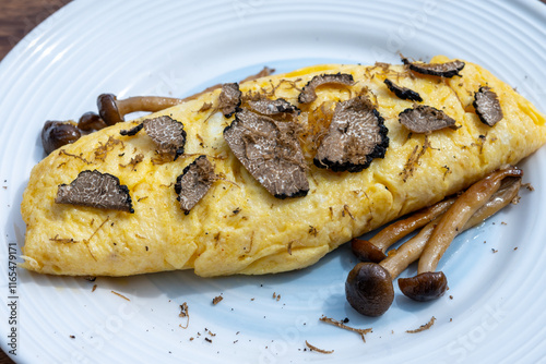 French omelette with mushrooms, fresh farmers eggs and black summer truffle mushroom in pieces for making truffle dishes with tasty aroma photo