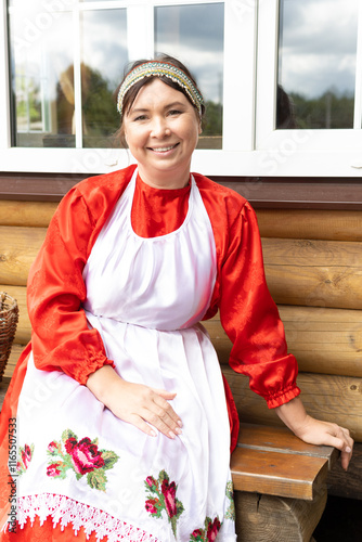 a woman in a national Udmurt costume. small nations. A village woman sits at a wooden house photo