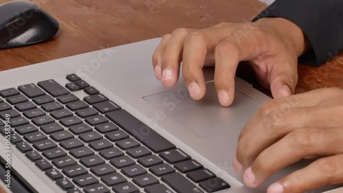 Stylish male employee in black shirt working online on computer in office. Close-up of a manager's hands doing browsing activity at work desk.