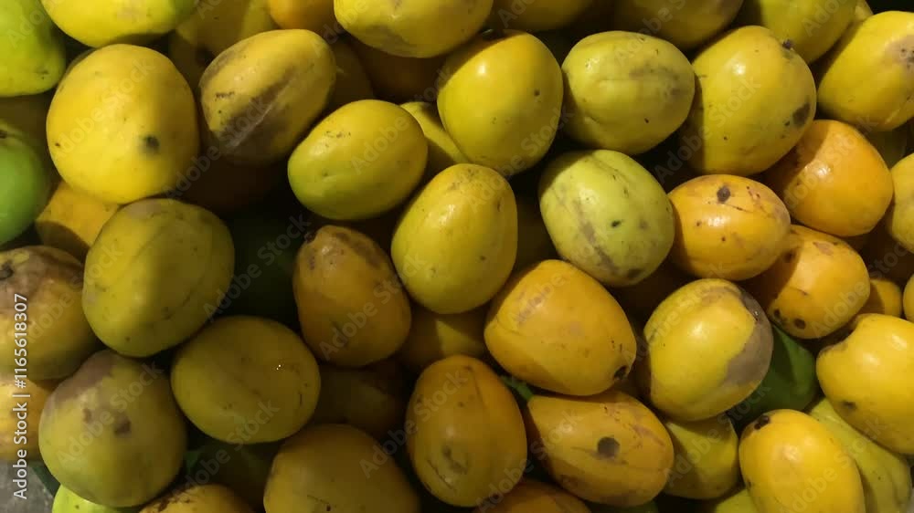 A market display of fresh kedondong fruits (ambarella), featuring bright yellow and green shades.