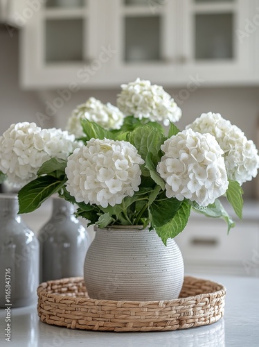 Elegant white hydrangeas in a textured vase on a kitchen countertop with natu...