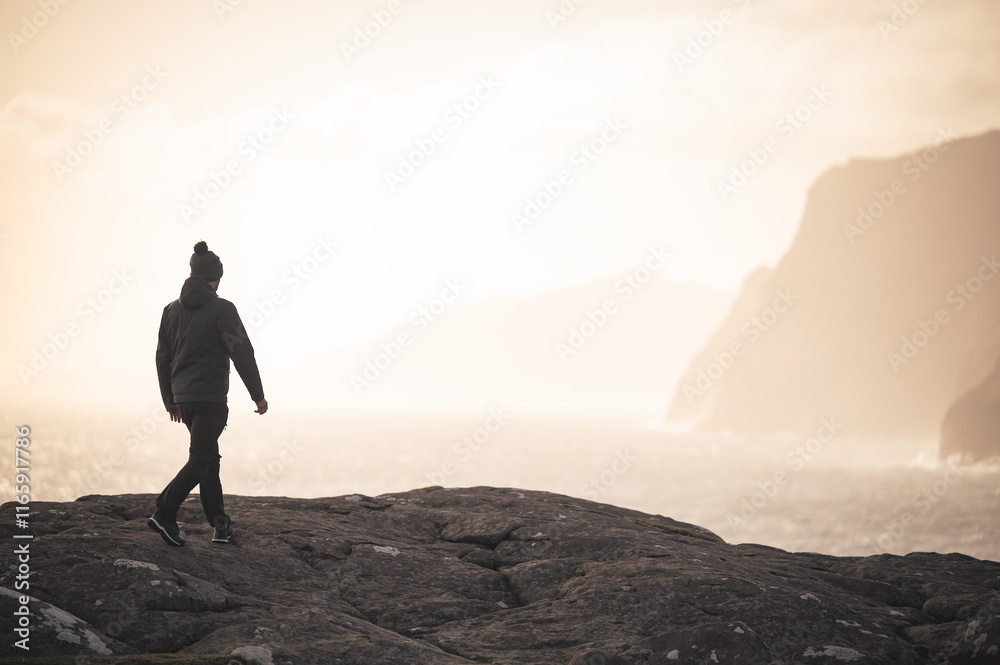 silhouette o f a man in the cliffs over the atlantic sea in Faroe Island at sunset silhouette o f a man in the cliffs over the atlantic sea in Faroe Island at sunset