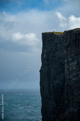 Cliff rock in the atlantic sea in Faroe Island with a silhouette of a man