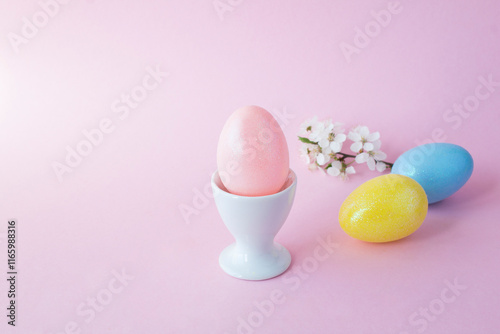 Pink easter egg in the white egg cup on the pink  background. Close-up. Copy space. photo