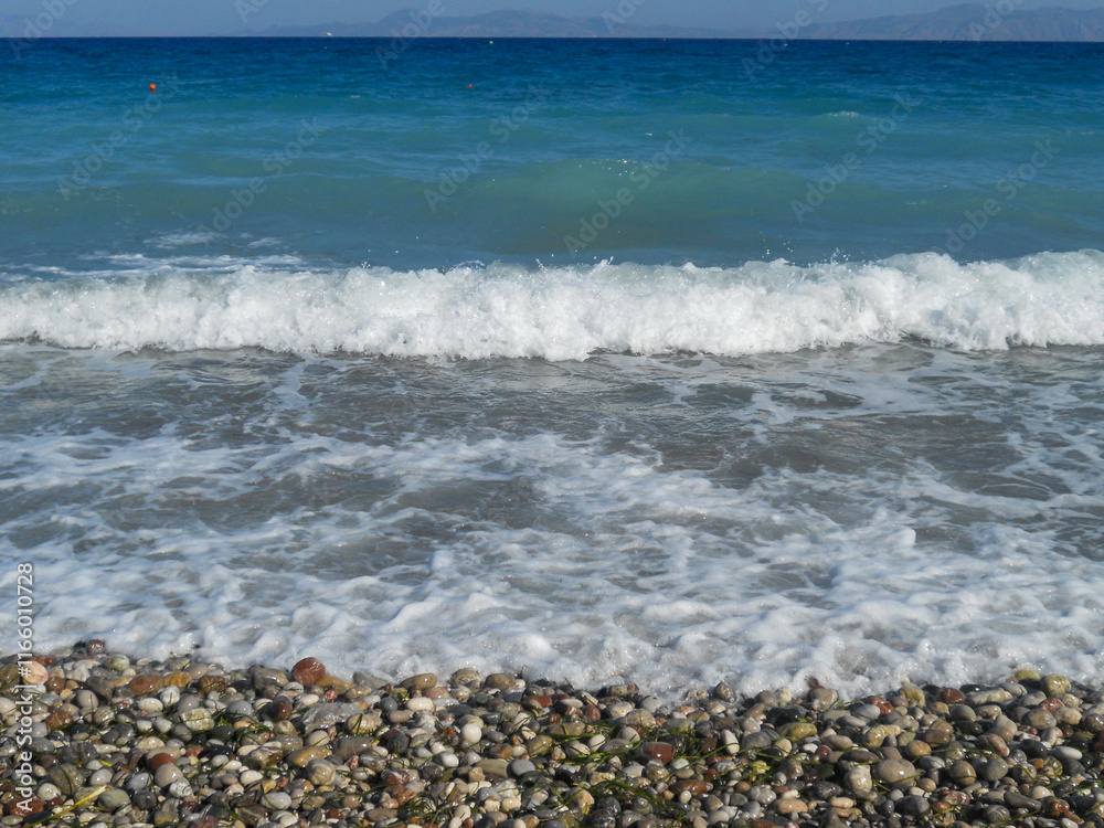 Waves lap gently at a colorful pebble beach Waves lap gently at a colorful pebble beach