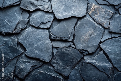 A close-up shot of a rough-textured black stone wall with intricate patterns and cracks photo