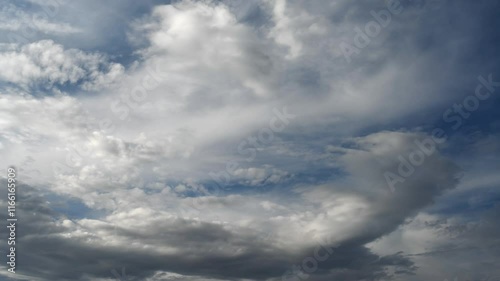 Time lapse of white and gray clouds moving across a dark blue sky.
