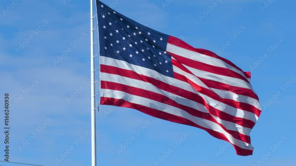 American flag on sky. The flag flutters in the wind. The video was shot in 60 fps to make slow motion possible.