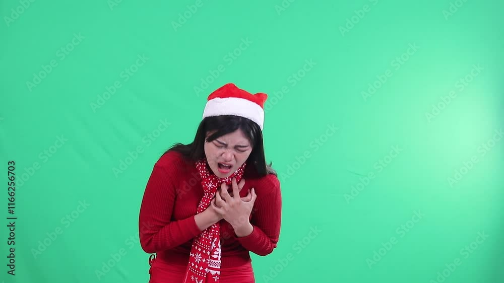 portrait of adult ladies showing heart pain expression while holding heart area, wearing Christmas sweater, Santa hat and scarf on green background,green screen portrait of adult ladies showing heart pain expression while holding heart area, wearing Christmas sweater, Santa hat and scarf on green background,green screen