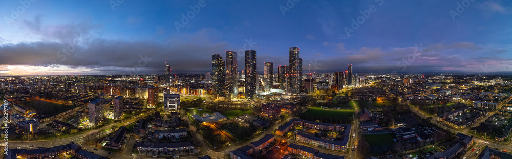 Obraz premium A captivating aerial shot of Manchester during dusk, showcasing the city's skyline with an enchanting blend of city lights and fading twilight colors.
