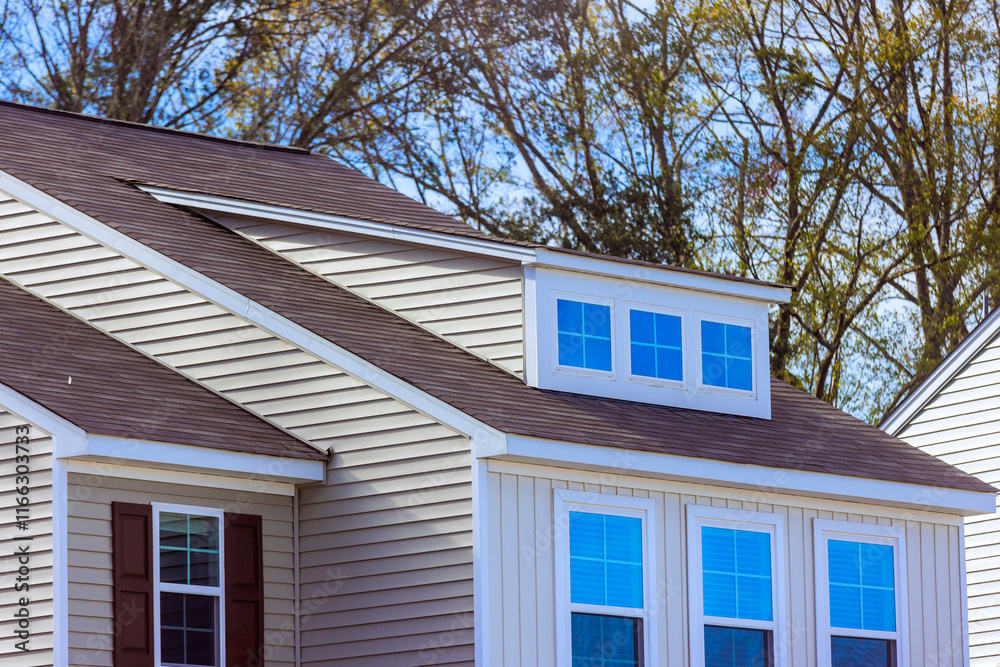 Contemporary house featuring peaked roof, large windows showcases with white siding at American town enhancing its architectural details modern design. Contemporary house featuring peaked roof, large windows showcases with white siding at American town enhancing its architectural details modern design.
