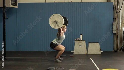 determined female power lifter lifting heavy weights over her head,