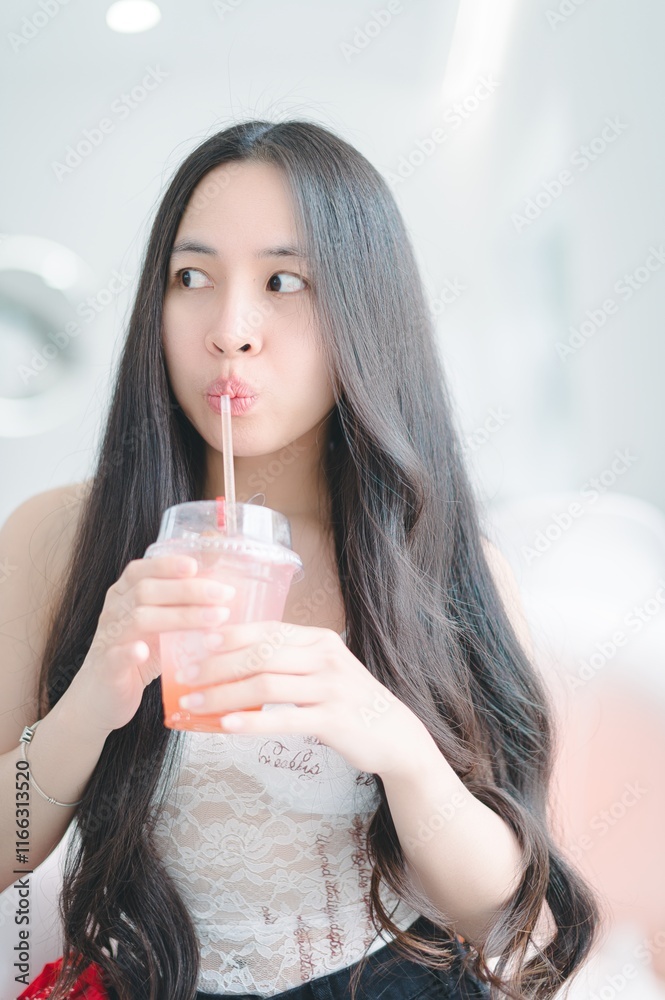 Young Woman Enjoys Refreshing Drink in Bright Indoor Setting Young Woman Enjoys Refreshing Drink in Bright Indoor Setting