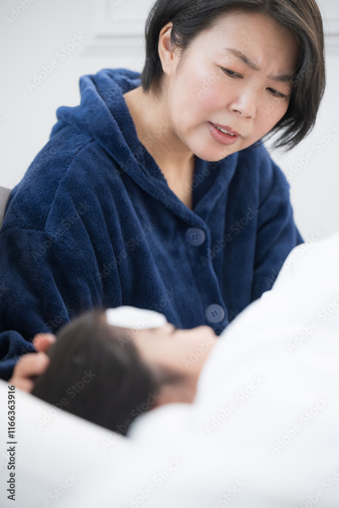 子供の風邪を看病する母親のイメージ 発熱の心配をする 子供の風邪を看病する母親のイメージ 発熱の心配をする