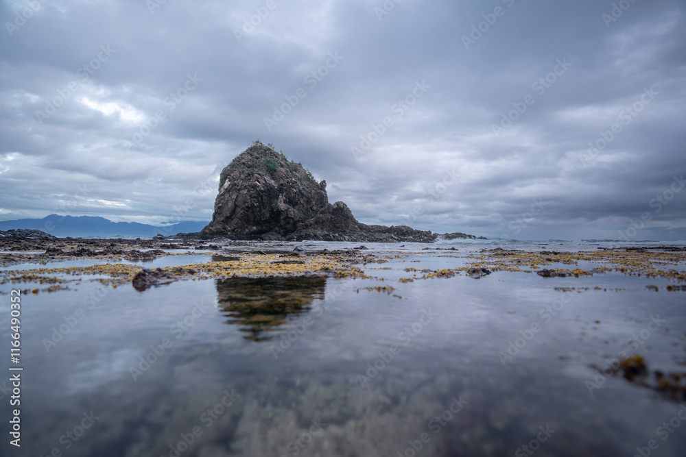 Dramatic coastal scene of Diguisit, Aurora featuring rugged rock formations, under a fast-moving, moody clouds. Calm water reflects the rich tones of the sky, creating a striking and seascape. Dramatic coastal scene of Diguisit, Aurora featuring rugged rock formations, under a fast-moving, moody clouds. Calm water reflects the rich tones of the sky, creating a striking and seascape.
