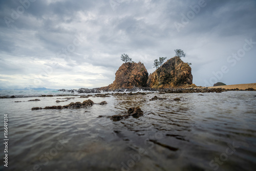 Dramatic coastal scene of Diguisit, Aurora featuring rugged rock formations, under a fast-moving, moody clouds. Calm water reflects the rich tones of the sky, creating a striking and seascape. photo