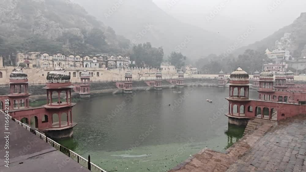 Pond surrounded by Majestic City Palace of Alwar Amidst Rugged Hills and Morning Mist
