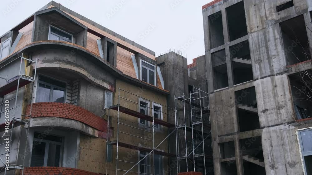 Construction Progresses on a Modern Building With Scaffolding at a Cloudy Location During the Afternoon Construction Progresses on a Modern Building With Scaffolding at a Cloudy Location During the Afternoon