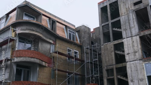 Construction Progresses on a Modern Building With Scaffolding at a Cloudy Location During the Afternoon