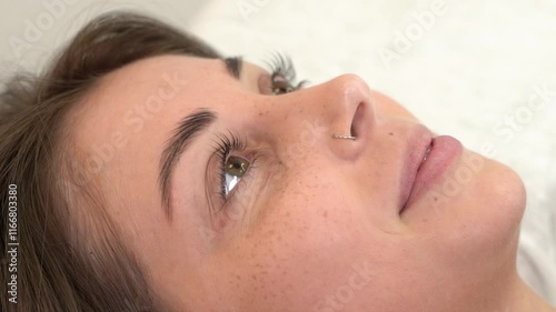 A beautiful young girl opens her eyes after eyelash lamination. Close-up, slow motion