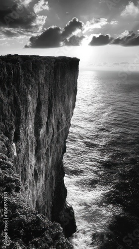 Dramatic rocky cliffside overlooking a turbulent seascape with crashing waves and ominous storm clouds in the distance  A moody black and white landscape showcasing the power and beauty of nature