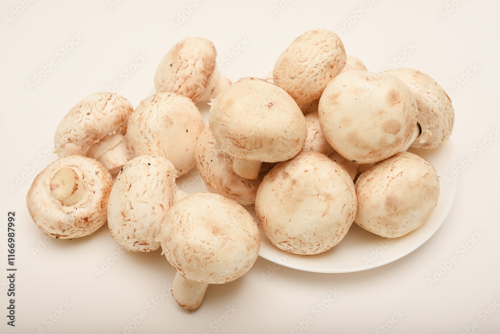 Fresh champignons on a white plate. Mushrooms on a white background. Fresh champignons on a white plate. Mushrooms on a white background.