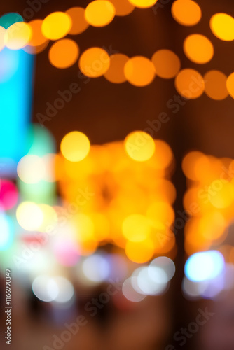 A blurred image featuring a series of warm orange bokeh lights, creating a dreamy and festive atmosphere. The lights are scattered and form abstract patterns against a soft background. photo