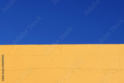Part of a yellow wall against a blue sky. Blue and yellow, divided into two parts background