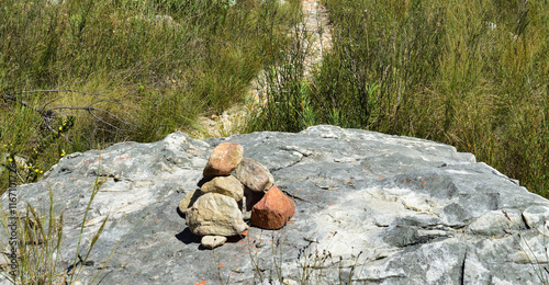 A cairn is a human-made pile of stones raised for a purpose, often as a marker on a hiking trail photo