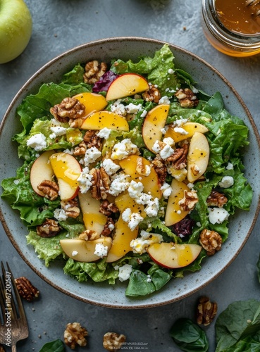 Fresh apple walnut salad with goat cheese and honey dressing on a marble coun...