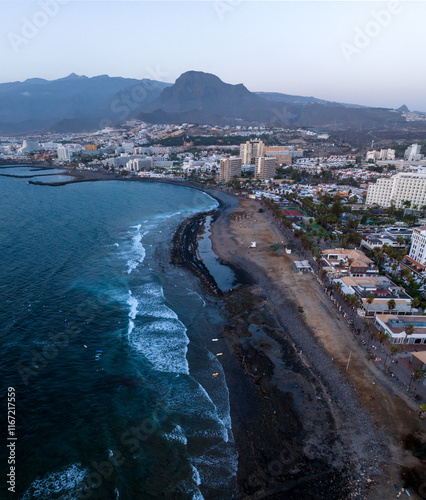 The captures the stunning beach of Tenerife, covered with unique volcanic black sand. The Atlantic Ocean gently washes the shore, in line coast costa Adeje. photo