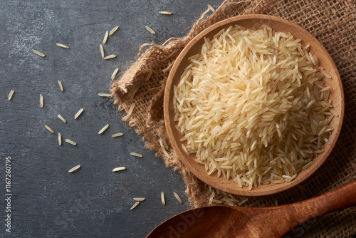 close-up of raw basmati rice grains on black textured table top surface, creamy white color grainy food taken straight from above with copy space